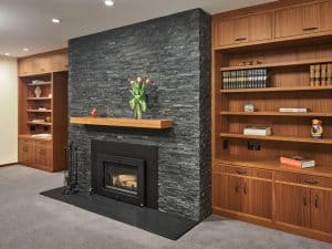 Stylish basement remodeling project featuring a modern fireplace with a slate accent wall and built-in