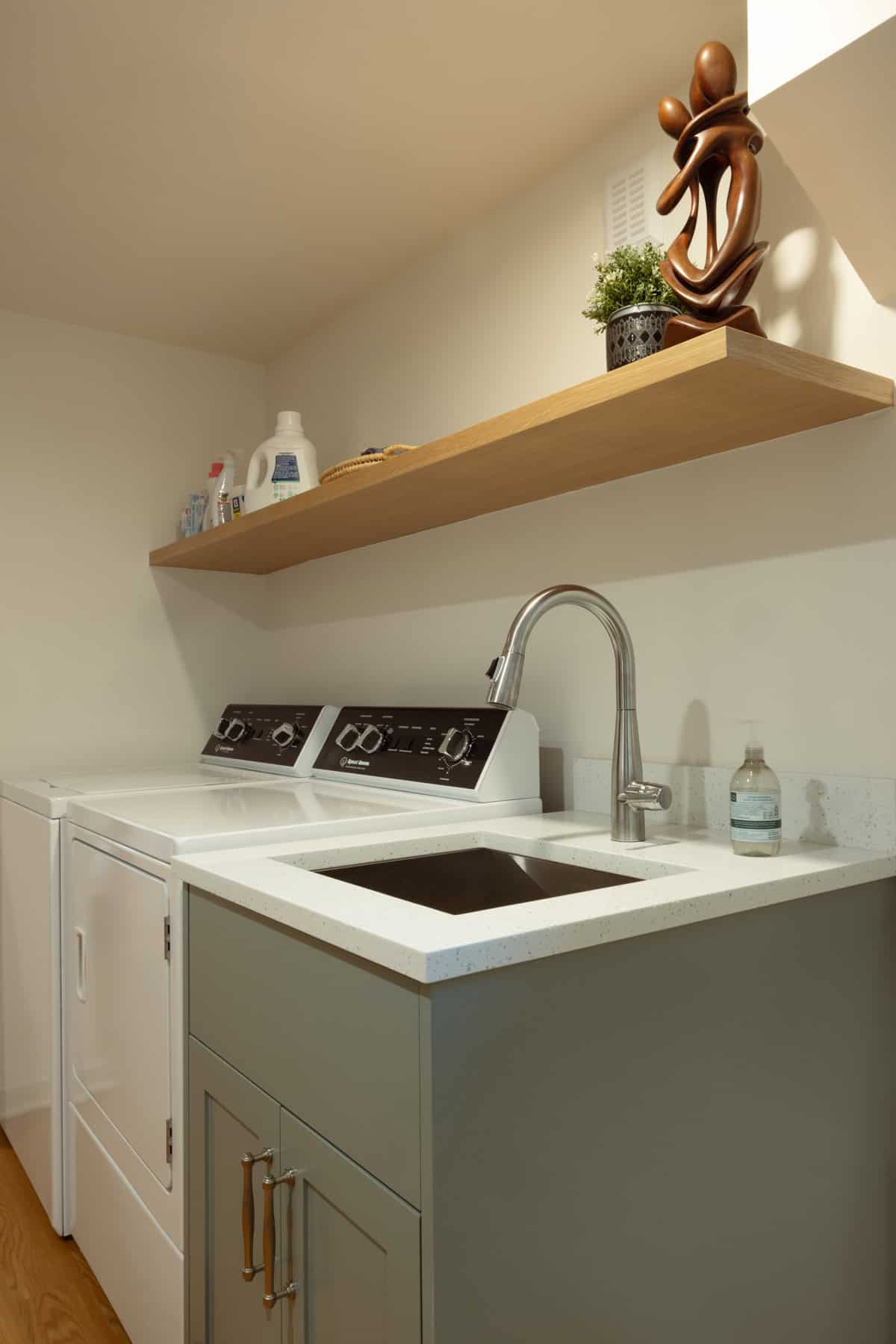 Finished basement laundry room remodel with custom shelving and utility sink by ReCraft Home Remodeling in Portland.