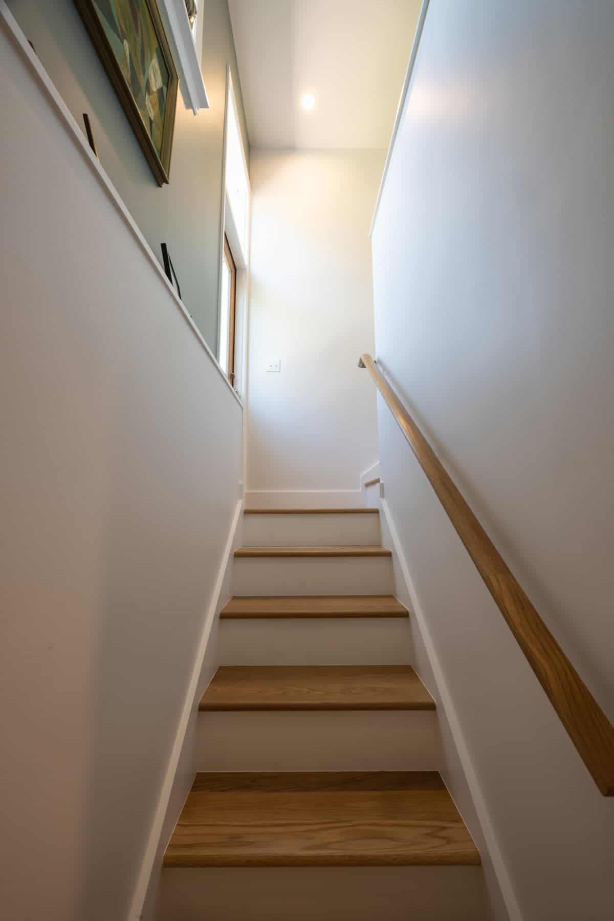 Finished basement renovation with wooden stairs and railing in Portland.